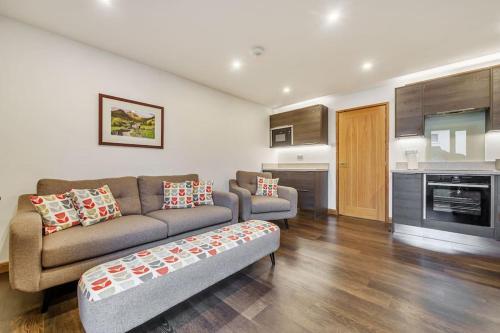 a living room with a couch and a kitchen at Modern Bowness-on-Windermere Flat - Free Parking in Bowness-on-Windermere
