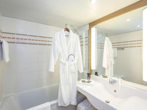 y baño blanco con lavabo y bañera. en Novotel Perpignan Nord Rivesaltes, en Rivesaltes