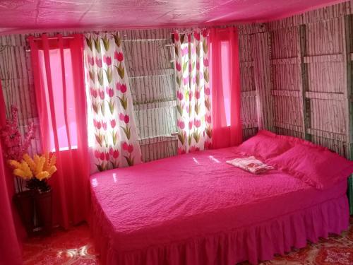 1 dormitorio con cama rosa y cortinas rosas en Jeremiah Homestay near Masasa Beach, en Batangas