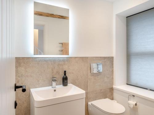 W łazience znajduje się umywalka, toaleta i lustro. w obiekcie Beach Haven w mieście Arnside