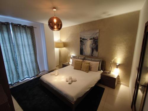 St Julians - Balluta 2 bedroom apartment في سانت جوليانز: غرفة نوم مع سرير مع وجود شمعتين عليه