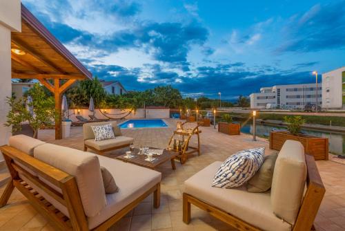 eine Terrasse mit Gartenmöbeln und einem Pool in der Unterkunft Villa Rita I in Nin