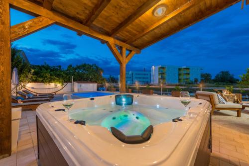 eine Whirlpool-Badewanne auf einer Terrasse mit Weingläsern in der Unterkunft Villa Rita I in Nin