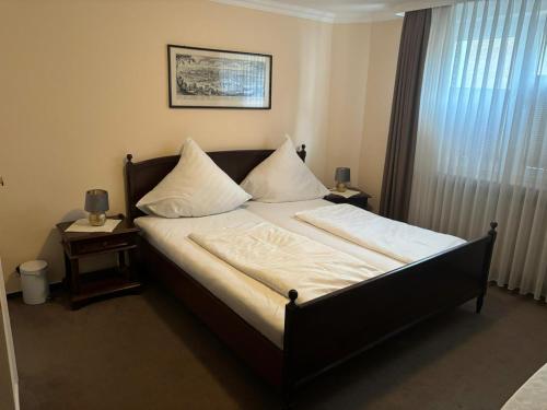 1 dormitorio con 1 cama con sábanas y almohadas blancas en Gästehaus Mietz, en Bad Neuenahr-Ahrweiler