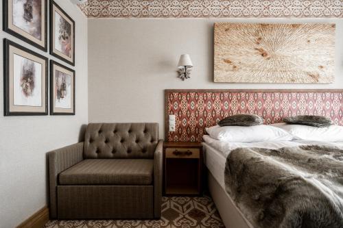 a bedroom with a bed and a chair at Apartamenty Aries Residence Bukowina in Bukowina Tatrzańska