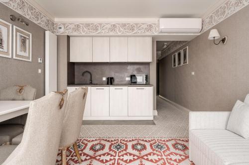 a kitchen with white cabinets and a table and a couch at Aries Residence Bukowina in Bukowina Tatrzańska