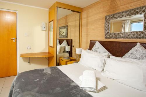 a bedroom with a large bed with a mirror at Ocean Breeze Hotel in Strand