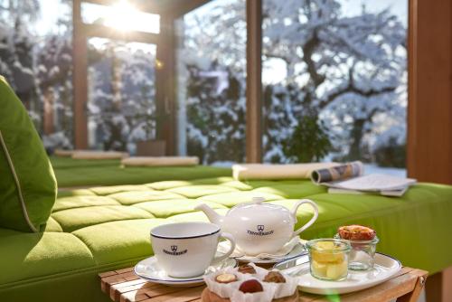 a room with a green couch with tea cups on a table at Relais & Châteaux Hotel Tennerhof in Kitzbühel
