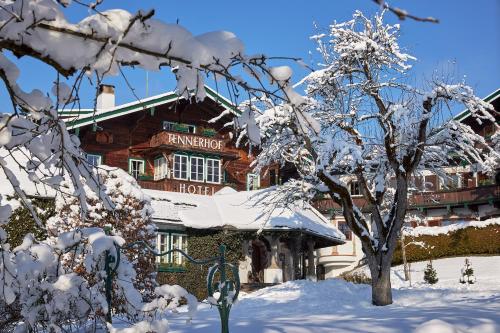 a snow covered building with a tree in front of it at Relais & Châteaux Hotel Tennerhof in Kitzbühel