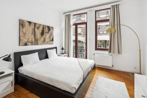 ein Schlafzimmer mit einem Bett und zwei Fenstern in der Unterkunft Apartment in Brussels, Degroux by Homenhancement SA in Brüssel