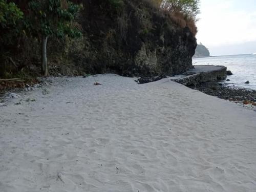a sandy beach next to the water and a cliff at Jeremiah Homestay near Masasa Beach in Batangas City
