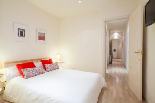 a white bedroom with a white bed with red pillows at Spot Smart Nomad in Barcelona