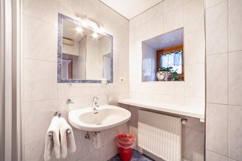 a white bathroom with a sink and a mirror at Wohnung Gravensteiner Schnalserhof in Laces