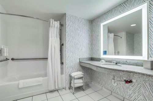 a bathroom with a tub and a sink and a mirror at Hilton Garden Inn Louisville-Northeast in Louisville