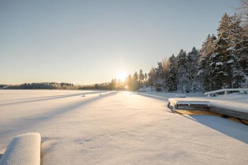 Asikkala的住宿－雷蒙卡基度假酒店，一条有雪覆盖的道路,在背后有太阳