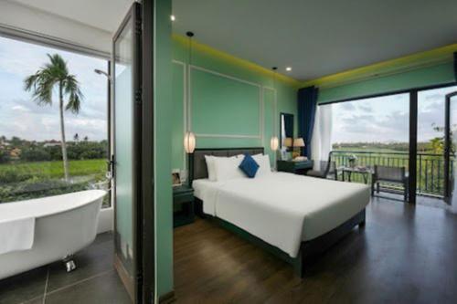 a bedroom with a bed and a bathtub and a bath tub at Serene Nature Hotel & Spa in Hoi An