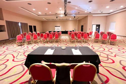 a conference room with a table and red chairs at Howard Johnson Hotel & Resort Funes in Funes