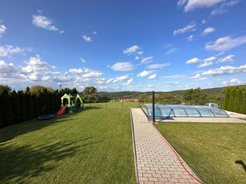 a park with a playground with a green lawn at Vila v Brdech s bazénem, infra saunou a vybavením in Malá Víska