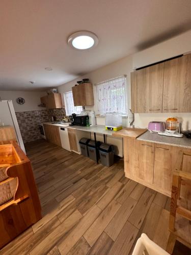 a large kitchen with wooden cabinets and a wooden floor at Vila v Brdech s bazénem, infra saunou a vybavením in Malá Víska