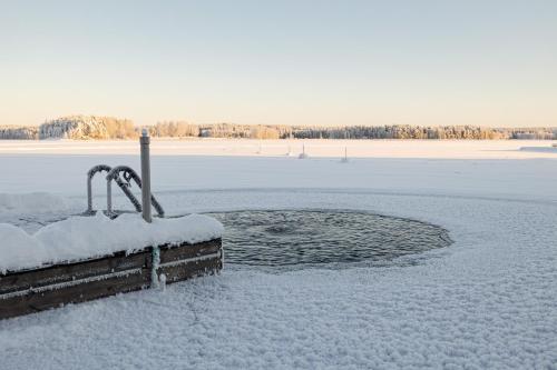 Lehmonkärki Resort في Asikkala: حقل مغطى بالثلج مع جزء من الماء