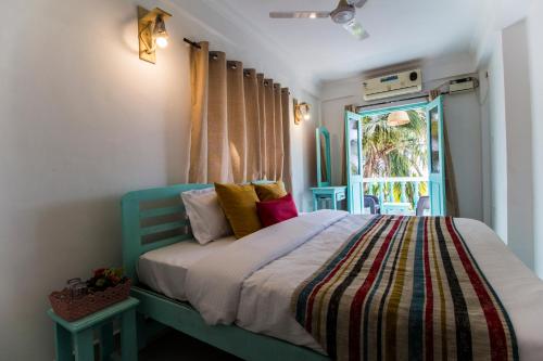 a bedroom with a bed with a colorful blanket and a window at TTH in Goa Velha