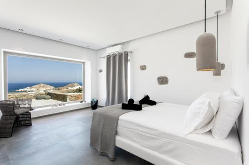 a bedroom with a bed and a large window at Myconian Platinum Villas in Kalafatis