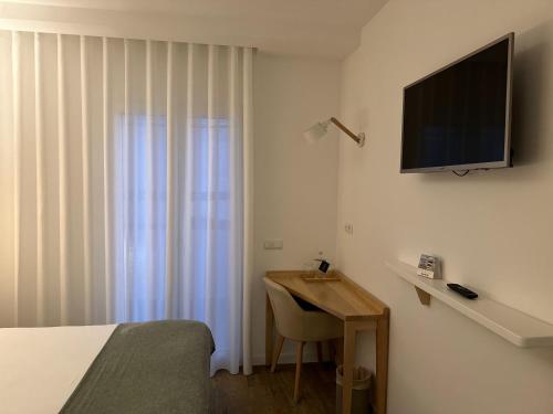 a bedroom with a bed and a desk with a television at Charm-In Center in Vila Nova de Milfontes