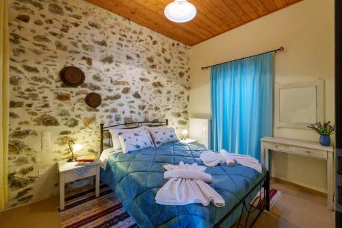 a bedroom with a bed with a blue comforter at Petrino House Lasithi in Agios Georgios