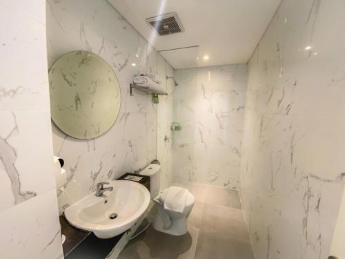 a white bathroom with a sink and a toilet at Facade Hotel by Azana in Tawangmangu