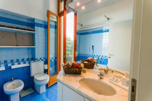 un bagno bianco e blu con servizi igienici e lavandino di Regal Villa with Como Lake View and Free Parking a Bellagio
