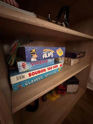 a book shelf with a stack of games on it at Vila v Brdech s bazénem, infra saunou a vybavením in Malá Víska