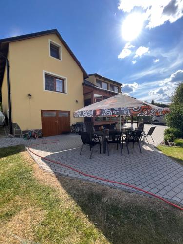 a patio with a table and chairs in front of a house at Vila v Brdech s bazénem, infra saunou a vybavením in Malá Víska