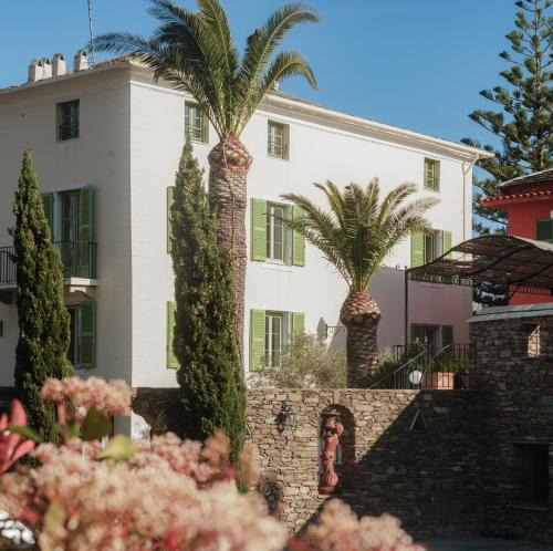 une maison avec des palmiers devant elle dans l'établissement Demeure Castel Brando Hôtel & Spa, à Erbalunga