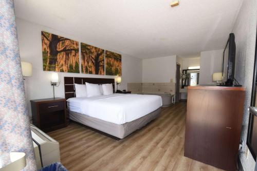 a bedroom with a large white bed and a flat screen tv at Days Inn by Wyndham Stuart in Stuart