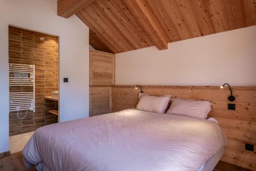 a bedroom with a white bed with a wooden wall at Chalet Ski Académie - Serre Chevalier in Saint-Chaffrey