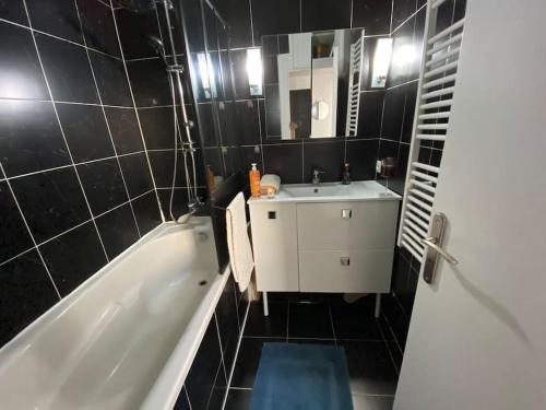 een badkamer met een wit bad, een wastafel en een spiegel bij La crème de la crème - Chantilly in Chantilly