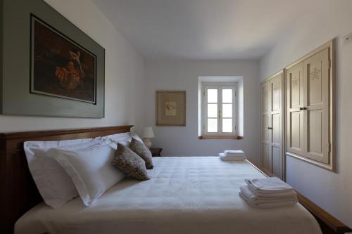 a bedroom with a bed with white sheets and a window at Borgo di Porciano Casa Maggiolino in Stia