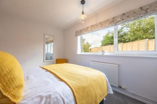 a bedroom with a bed with a yellow blanket and a window at The Saltings in Heacham