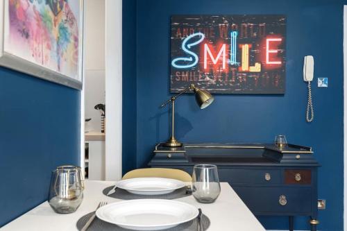 a dining room with a blue wall and a table with plates at Maidstone Central Studio Apartment in Kent