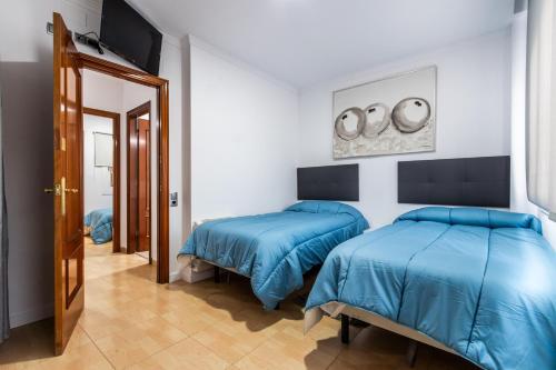 two beds in a room with blue sheets at BALARI in Sabadell
