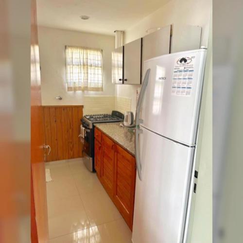 een keuken met een witte koelkast en een fornuis bij Zorzal Tempo in Esquel