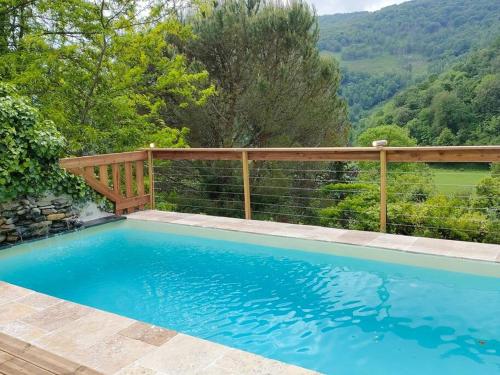 une piscine avec une clôture en bois et une terrasse en bois dans l'établissement paradis perdu piscine jacuzzi billard baby-foot, à Louvie-Juzon