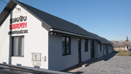 a white building with a black roof at Shubu GARDEN Vendégházak in Szilvásvárad