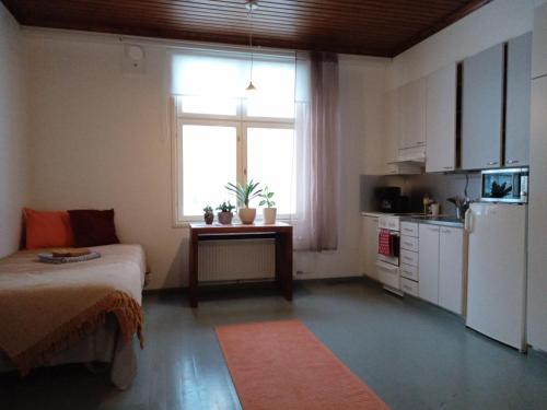 a room with a bed and a kitchen with a window at Warkhaus Apartments Korpela in Varkaus