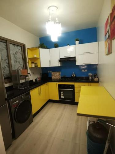 a kitchen with yellow and white cabinets and a table at Charmant appartement 15 minutes de la plage in Mohammedia