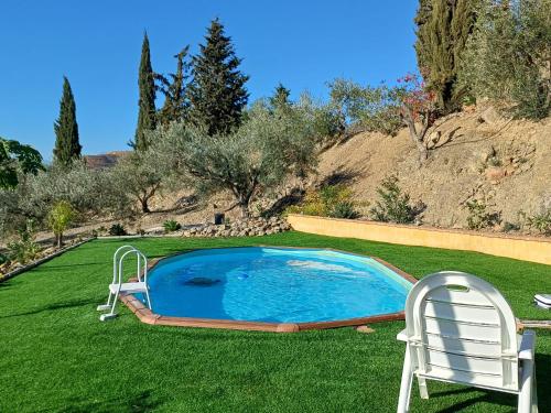 uma piscina no meio de um relvado com uma cadeira em rural loft with pool views peaceful place near the center em Málaga