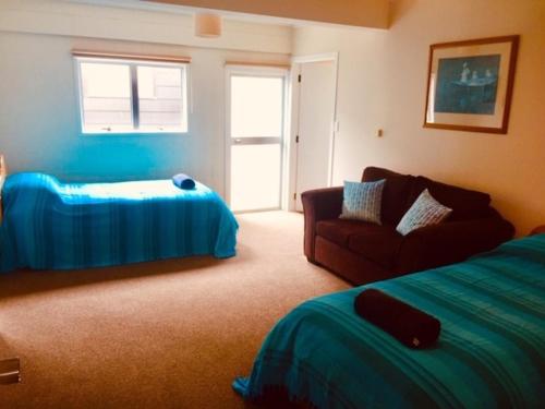 een slaapkamer met een bed, een bank en een raam bij Mollies Place - Waihi Beach Holiday Unit in Waihi Beach