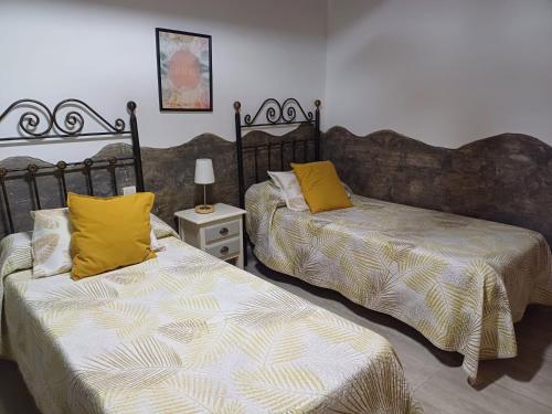 Duas camas com almofadas amarelas num quarto em rural loft with pool views peaceful place near the center em Málaga