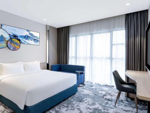 um quarto de hotel com uma cama branca, uma secretária e uma janela em Mercure Kuala Lumpur Trion em Kuala Lumpur