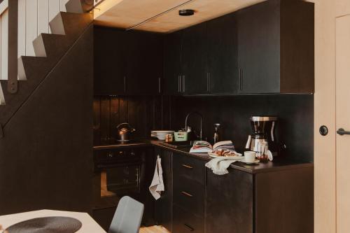 een keuken met zwarte kasten en een trap bij Błogostan in Jodłów